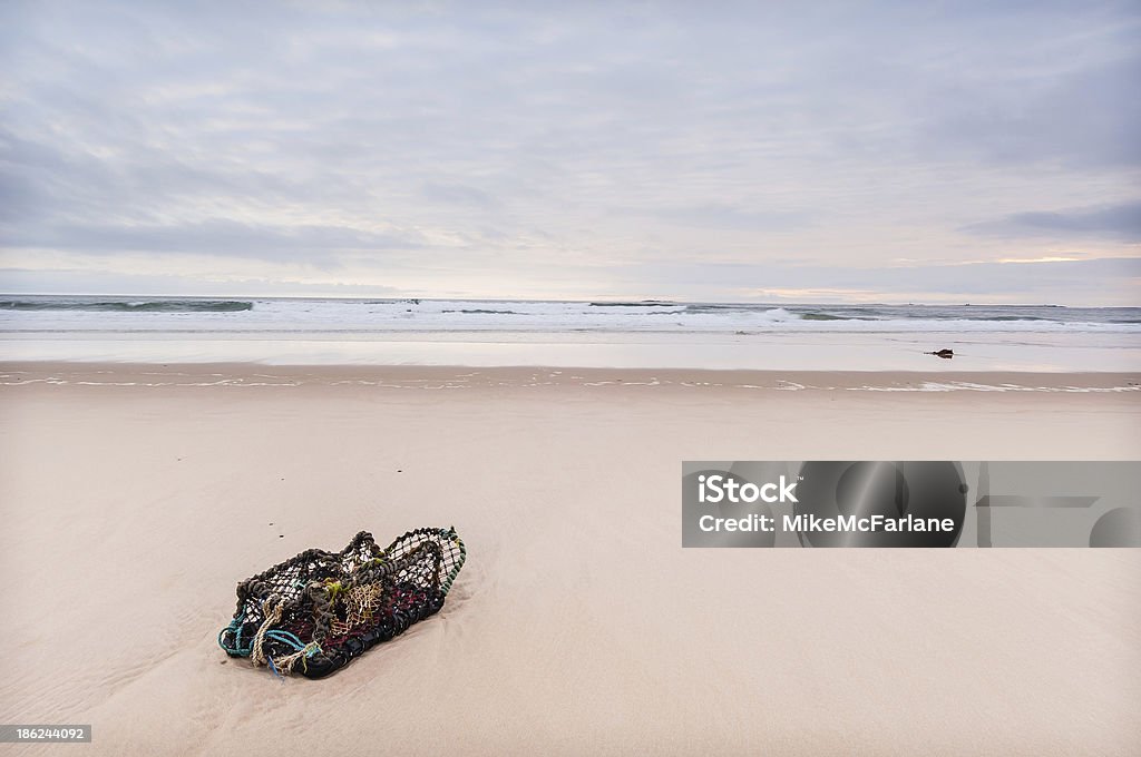 Solitary lobster pot lonely pale beach Bamburgh Northumberland A single lobster pot sits on a lonely pale beach near Bamburgh Northumberland Autumn Stock Photo