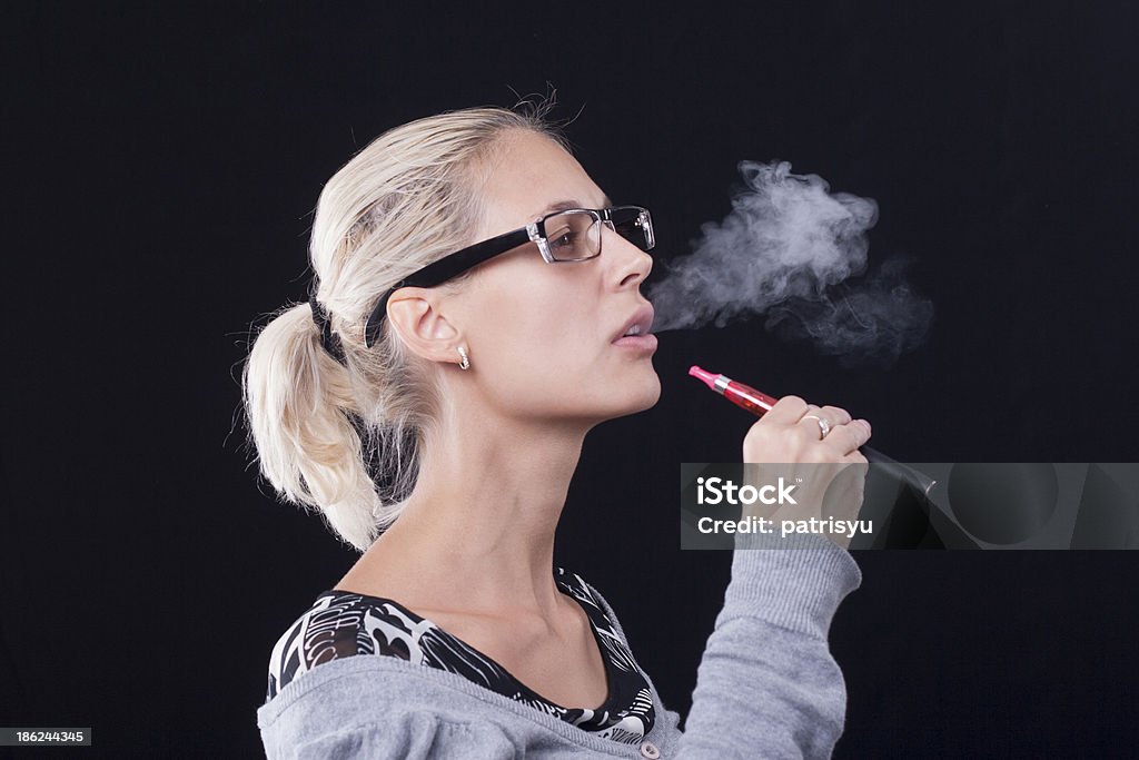 Giovane donna fumare e-cigarette - Foto stock royalty-free di Adulto