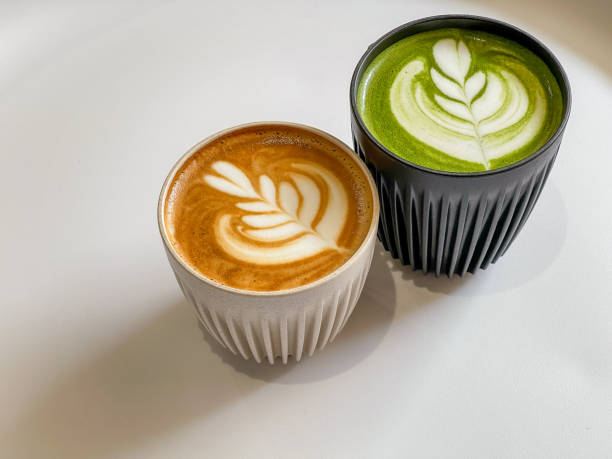 uma xícara de latte e matcha latte sobre mesa branca - latté cafe froth art cup - fotografias e filmes do acervo