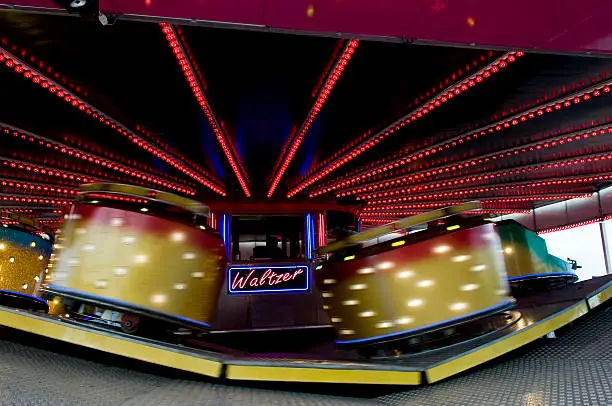 A waltzer ride going at speed at a fun fair. Lite with neon lights, Motion blur.