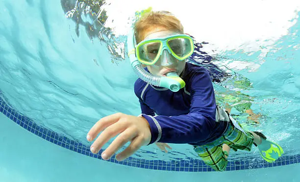 young boy swimming underwater in pool