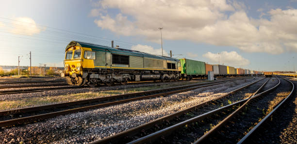 Profile view of a goods train with Intermodal wagons full of shipping container boxes for import and export in a yard or sidings