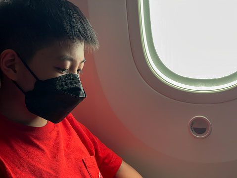 view of Asia boy with face mask sitting on the plane