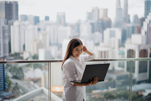istock Young woman using laptop on apartment's balcony 1862509943