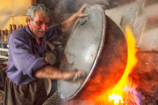 Karaman, Turkey - September 21, 2013: The tinsmith who repairs old copper, the man who polishes copper in the smoke, the tinsmith profession has begun to be forgotten.
​