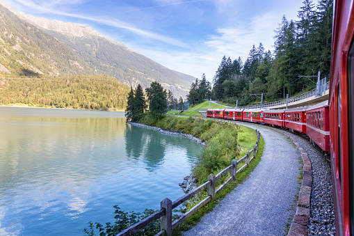Holidays in Switzerland - The Bernina Express passes Lake Poschiavo in the Bernina Mountains in the Alps. The well-known Bernina Railway, which has been a UNESCO World Heritage Site since 2008, links the spa resort of St. Moritz over the Bernina Pass with the Italian town of Tirano