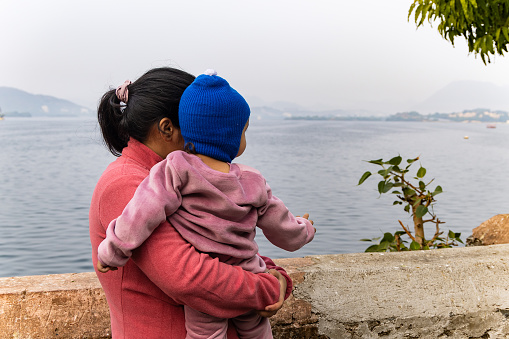 young mother with her son looking at mountain lake landscape at morning image is taken at Jagdish Temple udaipur rajasthan india.