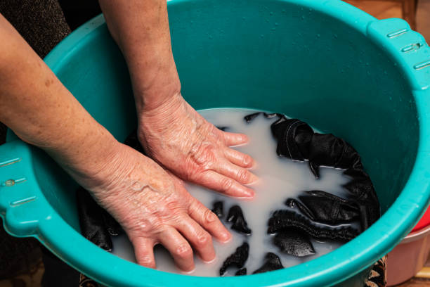 Grandma washes clothes in a poor neighborhood.Hand washing of household clothes stock photo