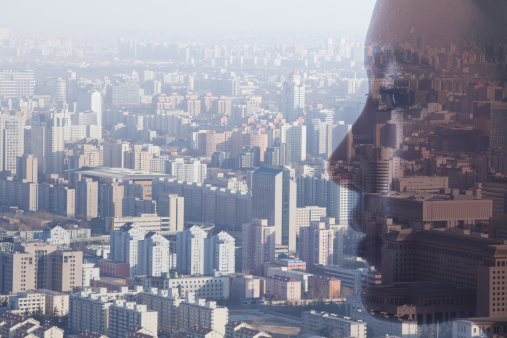 Double exposure of young woman's face over cityscape, side view
