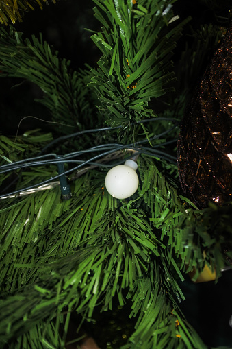 This striking image captures the exquisite simplicity of a single white bauble cradled within the evergreen embrace of a Christmas tree. The ornament's pristine surface reflects the tranquil light, offering a sense of peace and purity in the hustle of the holiday season. Each detail is meticulously displayed—a delicate frost-like pattern etched into the bauble's surface, the fine glitter catching the ambient light, and the dark green needles providing a contrasting backdrop that accentuates its simple beauty. The close-up angle invites viewers to pause and reflect, urging them to appreciate the smaller details that epitomize the spirit of Christmas. The soft focus on the surrounding branches adds a dreamy quality to the scene, creating an image that is not only visually striking but also evocative of the serene moments of joy that the holidays bring