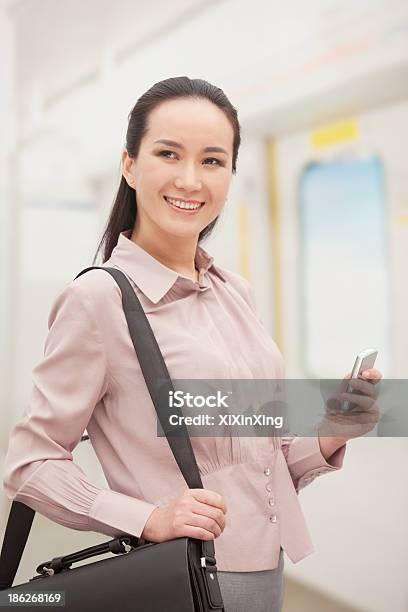 Sorridente Jovem Mulher Segurando Um Telemóvel - Fotografias de stock e mais imagens de 25-29 Anos - 25-29 Anos, A usar um telefone, Adulto
