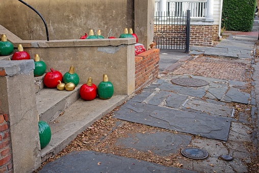 Festive pumpkins painted in Christmas colors on door steps in old town Charleston South Carolina. Slate sidewalks along Water street.