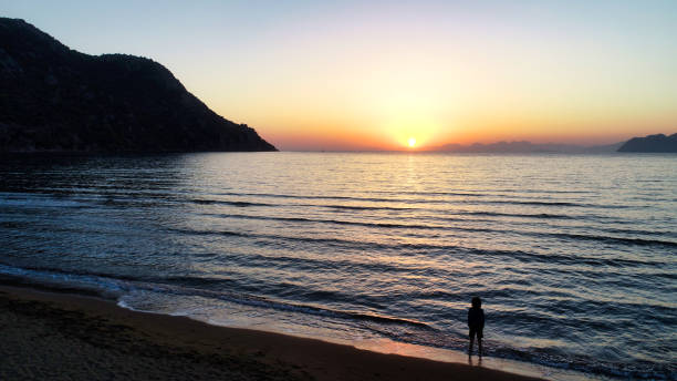 Waves gently lap at the shore under the golden light of a setting sun.