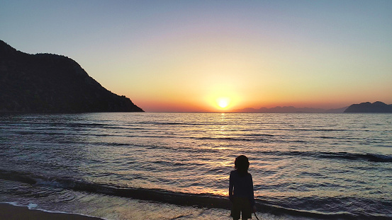 The sun’s final glow illuminates the beach, with a single figure enjoying the tranquility of twilight.