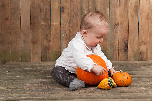 istock baby playing with pumkins in a barn 186269822