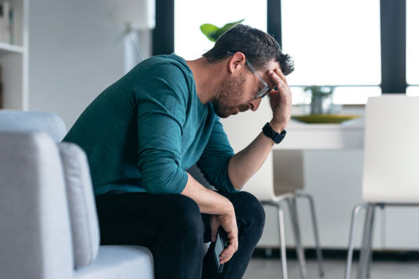 istock Worried mature man thinking about what he has read on his mobile phone while sitting on the couch at home 1862730120