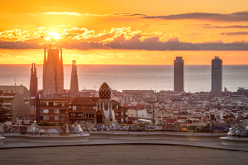Sun rises in Barcelona. View of the city from Parc Guell Park. The sun is over the Sagrada Familia between the clouds
