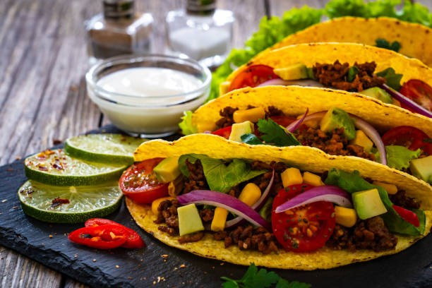 istock Tacos with ground beef, avocado, corn and fresh vegetables on wooden table 1862734266