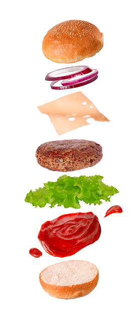 Burger levitation of ingredients bun, lettuce, cutlet, tomato, onion, ketchup on a white background
