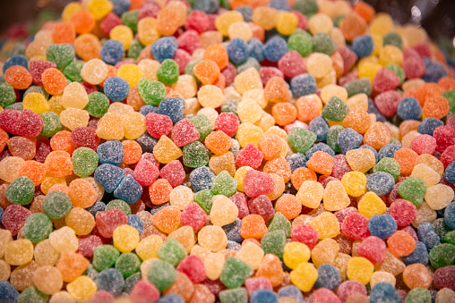 Five squared bowls with small red, yellow, blue, green and orange coated chocolate candies similar to m&ms in a squared bowl isolated on white background, top view