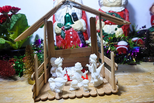 Crafted with exquisite attention to detail, this image captures the essence of the holiday spirit through a rustic wooden nativity scene. The figurines, with their artful simplicity, convene to retell the timeless story of the birth of Jesus. Each character, from the blessed Virgin Mary to the three Wise Men, is positioned with reverence and care. The warm glow of the scene suggests an inviting, gentle light, as if a single star illuminates the setting from above. The wood's natural grain and the figures' subtle hues evoke a sense of authenticity and tradition. This carefully arranged tableau invites contemplation and evokes a deep sense of peace, capturing the intimate and sacred moments of the Christmas narrative