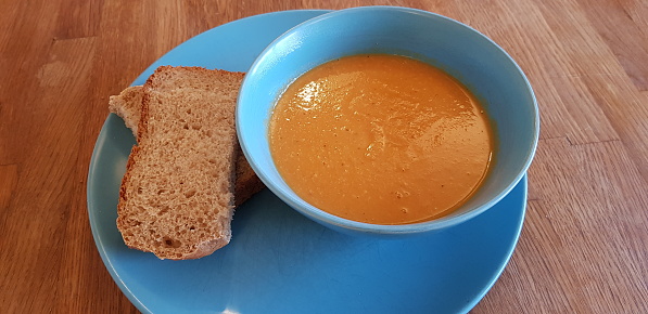 Homemade lentil and carrot soup served with bread in Glasgow Scotland UK