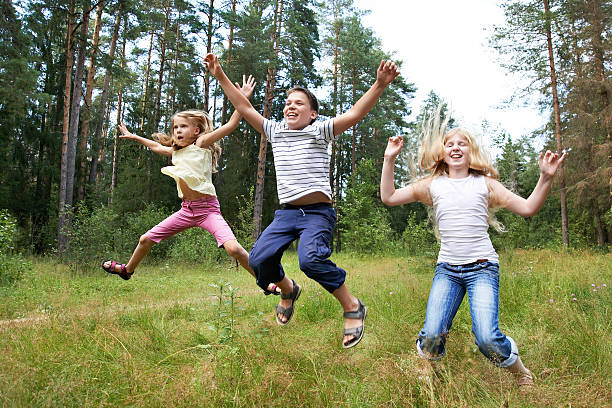 istock Children jump on lawn in summer forest 186281357