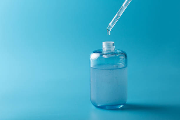 istock Serum pipette in close-up with a falling drop on a blue background, cosmetic packaging with a dispenser 1862826338