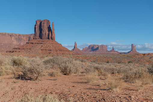 Tall spires and mesas of rich dark red rugged mountains near Monument Valley in Arizona and Utah of western USA in North America. This is part of the Navajo Nation in USA.  Nearest cities are Phoenix, Arizona, Salt Lake City, Utah, Denver and Durango, Colorado.