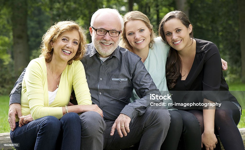 Madre, Padre e due figlie sorridente all'aperto - Foto stock royalty-free di Abbigliamento casual