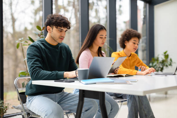 istock Diverse group of students sitting in university library with gadgets learning for exams, making online research 1862898242