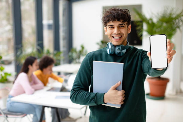 istock Positive european student guy showing smartphone with blank screen recommending educational app, coworking space 1862898762