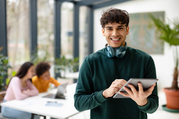 istock App for knowledge. Cheerful european guy students using tablet for video lesson, studying with friends in classroom 1862898766