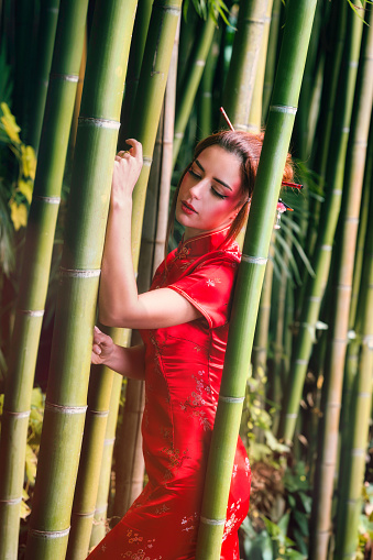 Experience the timeless beauty of a 25-year-old woman of European descent, captured in a series of vibrant portraits amidst a bamboo grove. Adorned in an elegant red Japanese dress, she embodies the harmony between Western culture and Japanese aesthetics. The warm hues of the kimono beautifully contrast against the lush green backdrop of bamboo, creating an enchanting atmosphere. Each shot reveals the model's natural grace, while the bamboo stalks provide a unique and soothing natural frame. Ideal for illustrating the fusion of fashion and nature, this portrait collection offers striking images for artistic, editorial, or advertising projects.