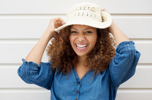 Portrait of a cheerful carefree woman laughing and wearing summer hat