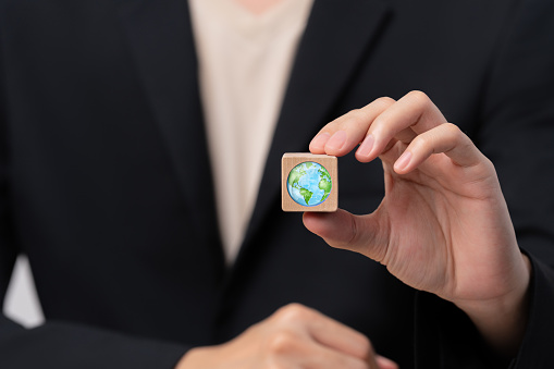 Businessman's hand holds a wooden block with a globe ,global warming concept,sustainable development and green business from renewable energy.