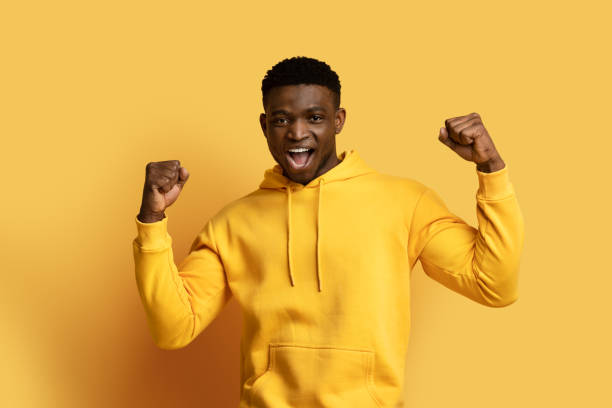 istock Thrilled young black man champion showing winner gesture on yellow 1862930174