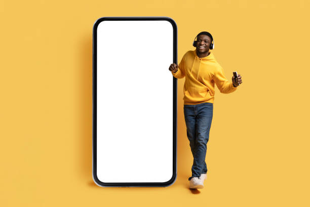 istock Thrilled black guy dancing by huge phone, using wireless headphones 1862930328