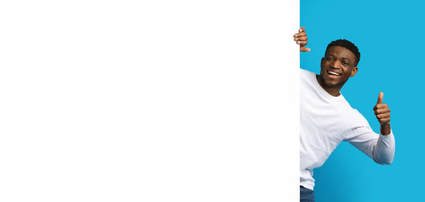 istock Positive young black guy next to blank white advertising board 1862930707