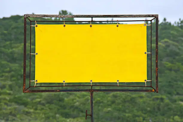 Yellow rusty sign with wood on the background.