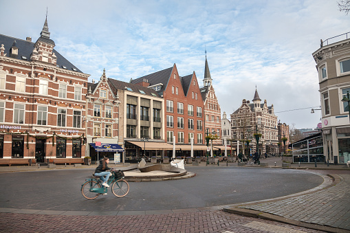 Breda, Netherlands - 2023, December 7 : A square with traditional architecture and a female cyclist in the Dutch town of Breda
