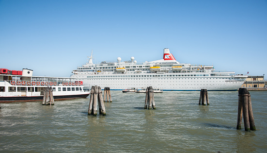 Venice Italy - May 10 2011; Cruise liner depart port with berthed ferry tied alongside  on sunny clear sky day.