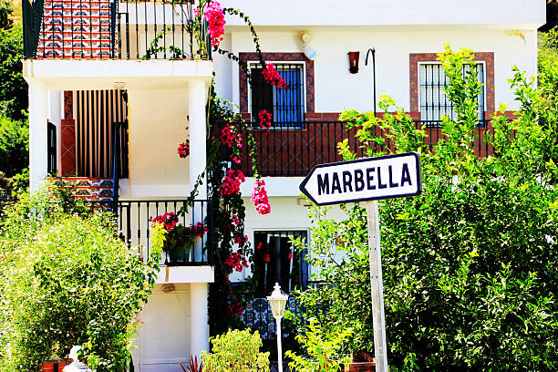 White arrow sign pointing towards Marbella in a village stock photo