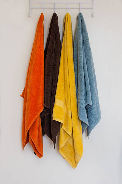 istock Four Colored Towels Hanging Against White Wall 186295774