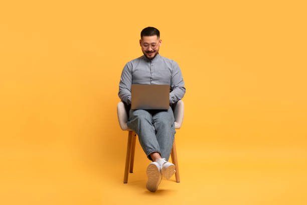 istock Online Education. Happy Young Asian Man Using Laptop While Sitting In Chair 1862957743
