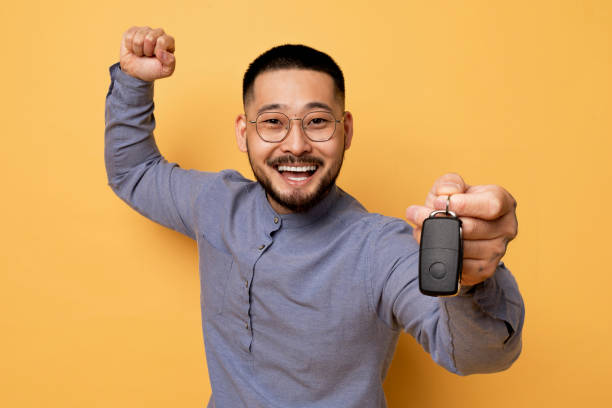 istock Funny Young Asian Guy Showing Car Key At Camera 1862958302