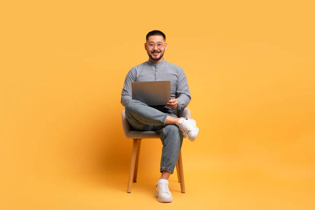 istock Freelance Career. Smiling Asian Man Using Laptop Computer While Sitting In Chair 1862958871