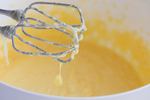 Electric mixer with dough with eggs in background.