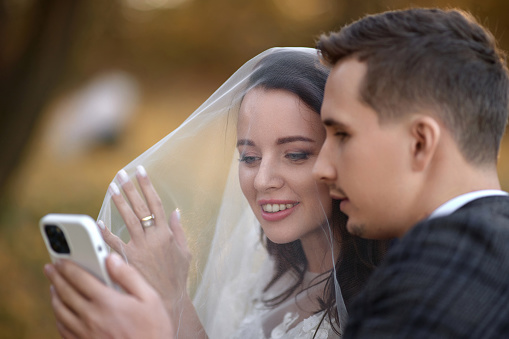 Beautiful bride and groom taking selfie with mobile phone in nature