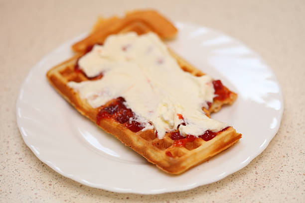 Delicious belgian waffle garnished with jam and whipped cream
